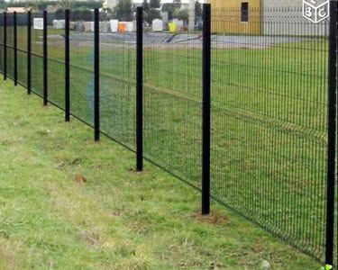 Clôture en panneaux de grillage soudé noir avec poteaux, délimitant un jardin gazonné. Simple et efficace.